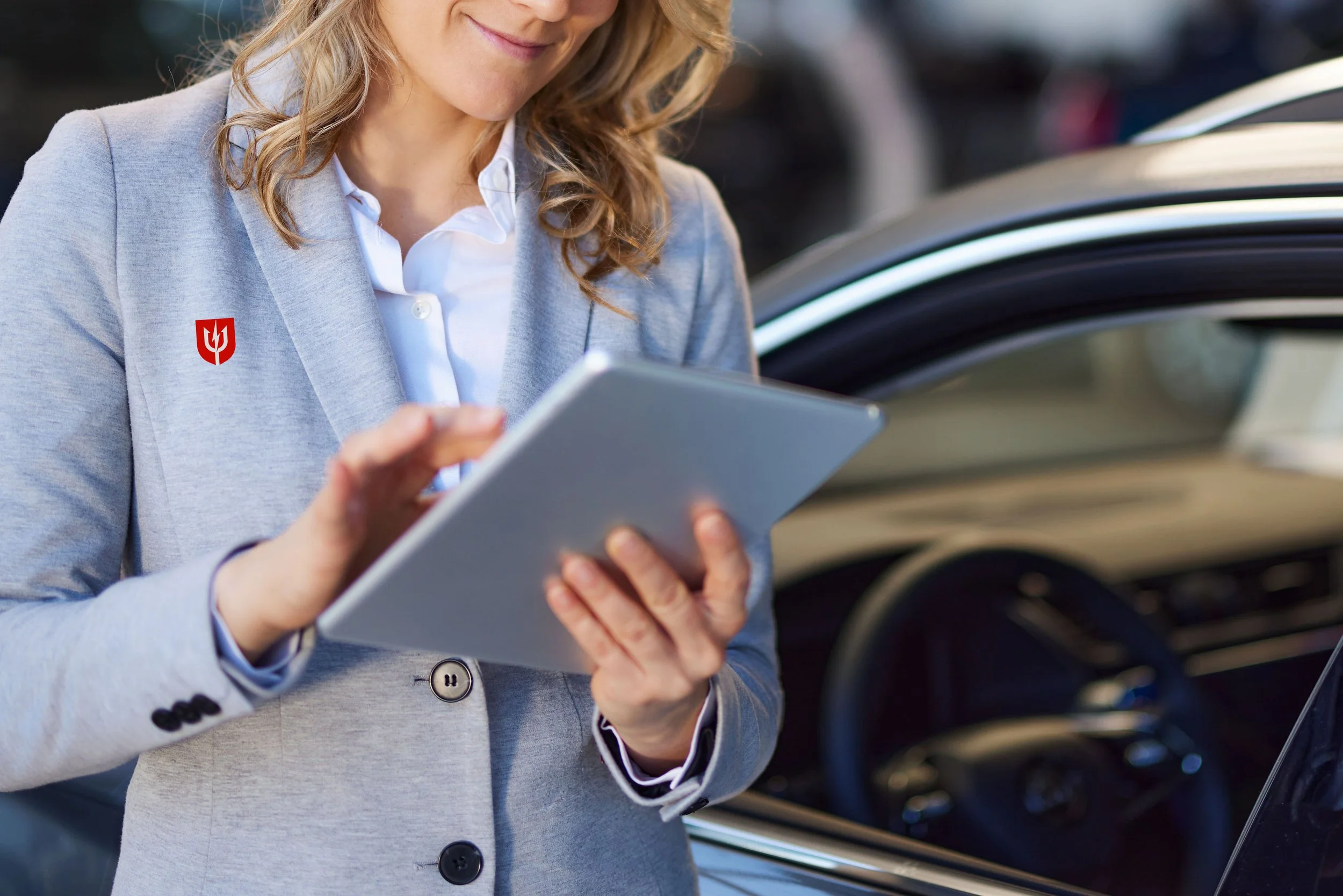 Recovered Trident marketing photograph of a person using a tablet beside a vehicle